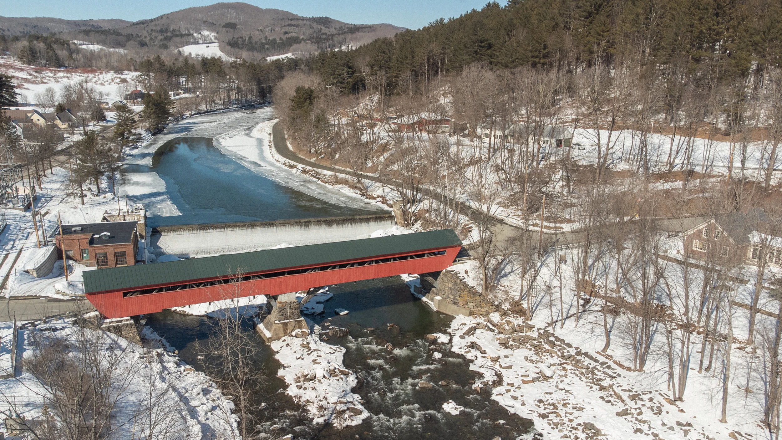 A red covered bridge in a snowy Vermont landscape