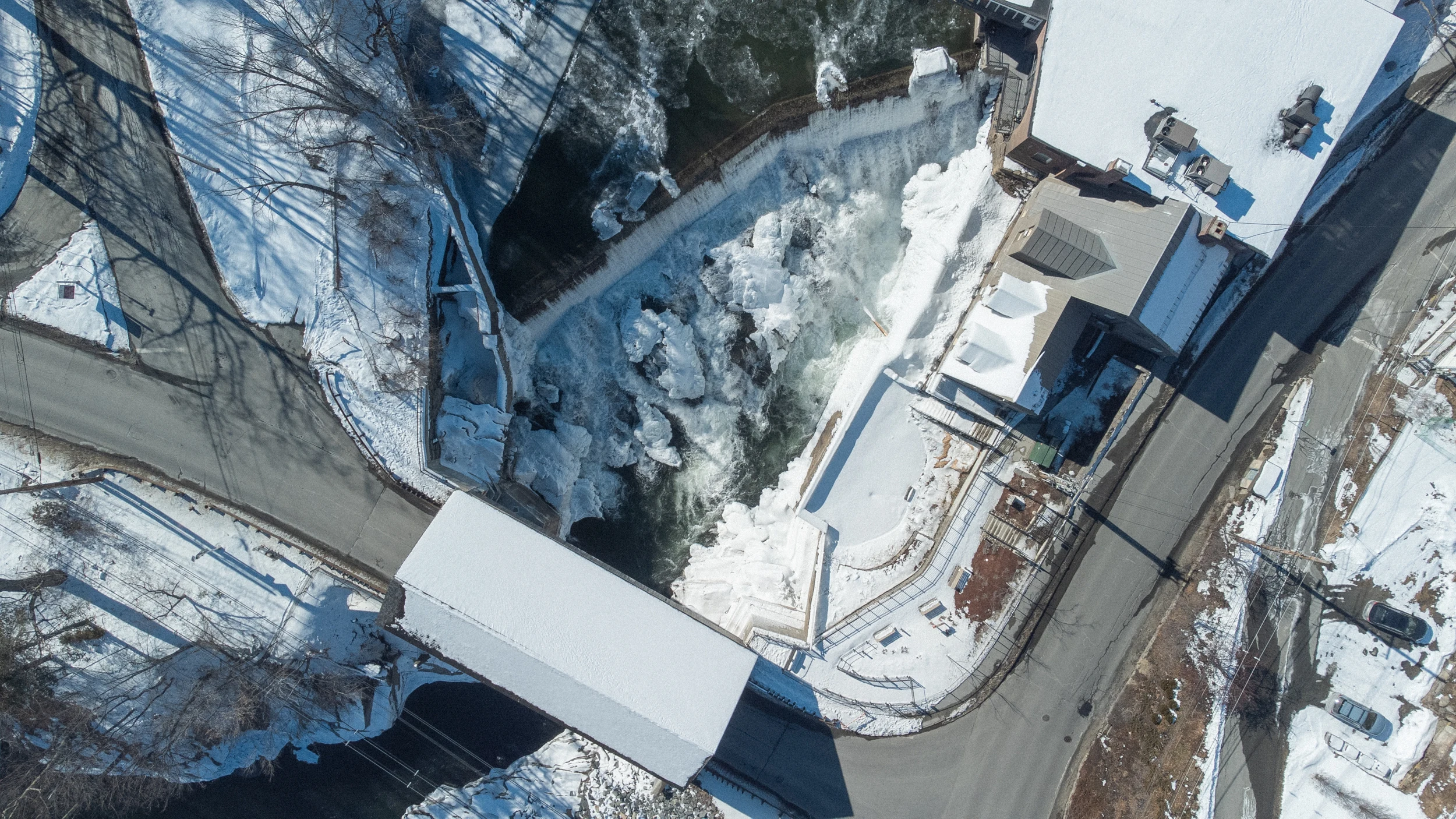 A covered bridge beside a frozen waterfall, seen from above