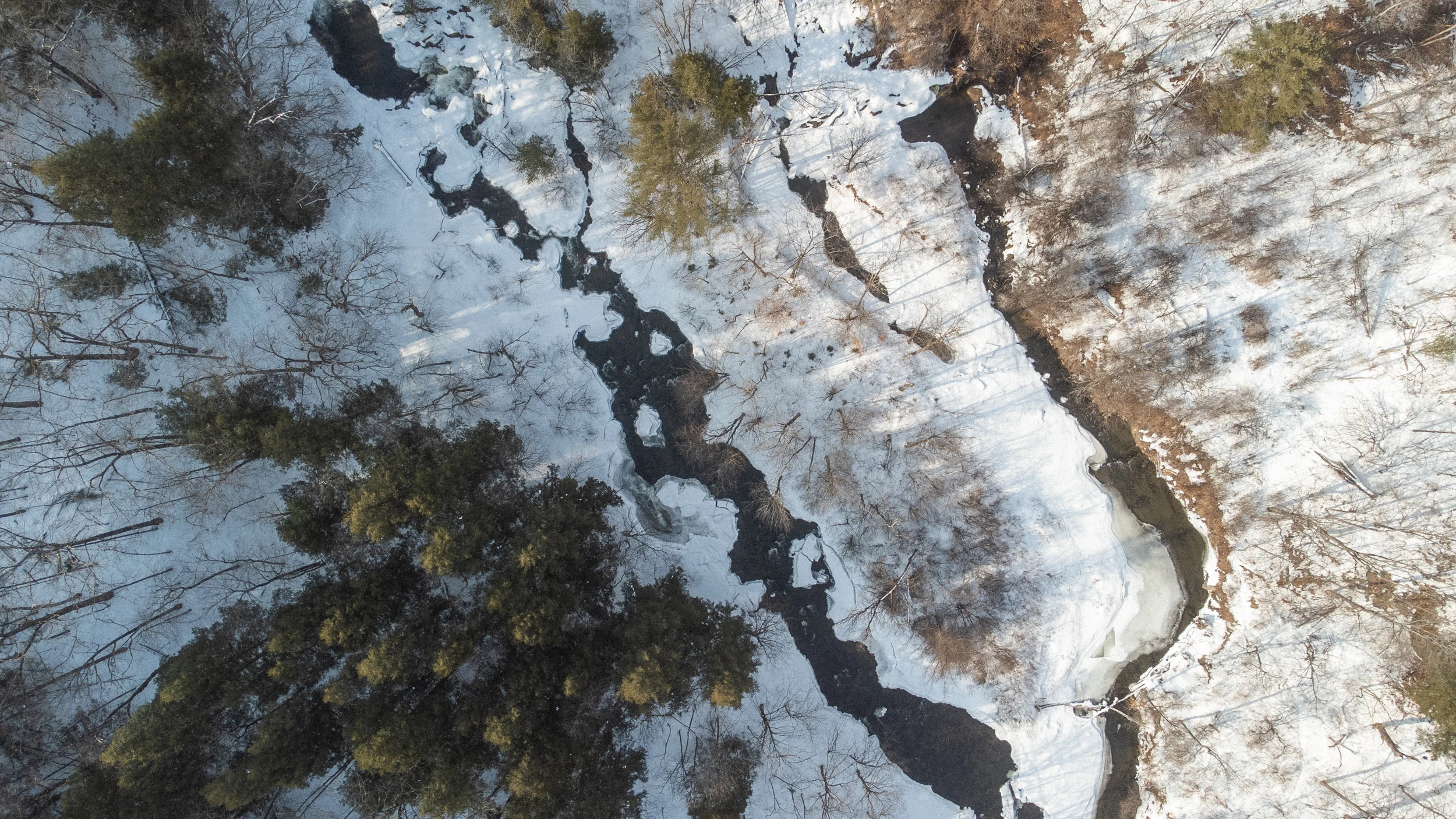 Dark river channels winding between snow and ice